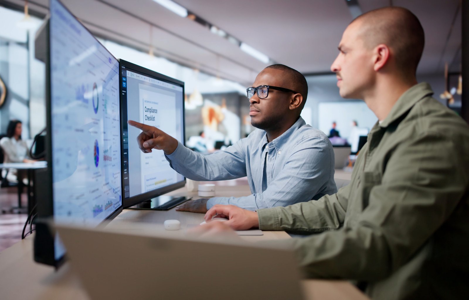 Two Men Analyze Compliance Data Together Using Regulatory Dashboard Tools.